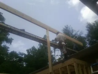 Carpenter setting a ridge beam over a new addition frame — Ice Dam Removal by Roofing Brothers in Pingree