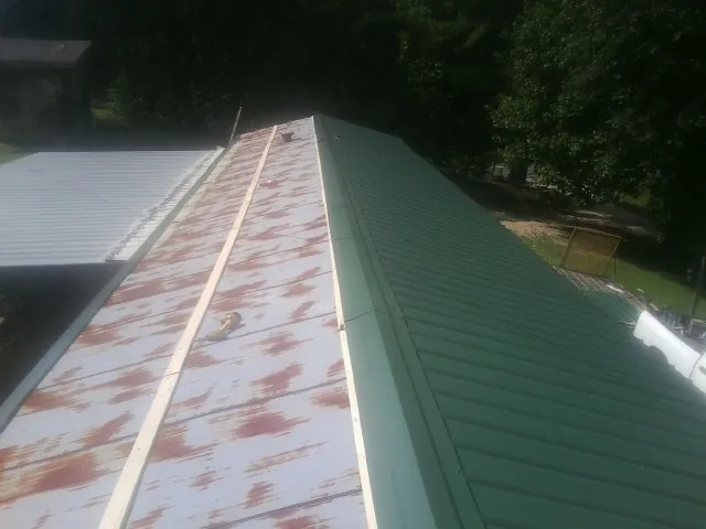 Old rusted panels beside newly installed green metal roofing — Wind Damage Roof Repair by Roofing Brothers in Pingree