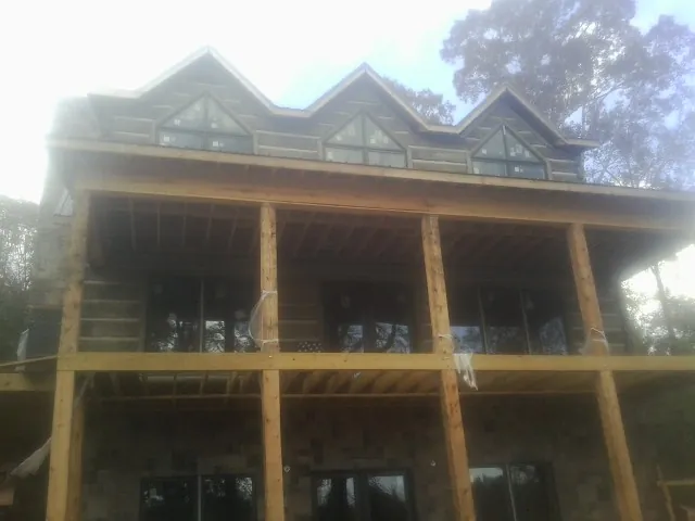 Dormers and porch framing on a large log home under construction — Roof Coating work by our crew in Pingree