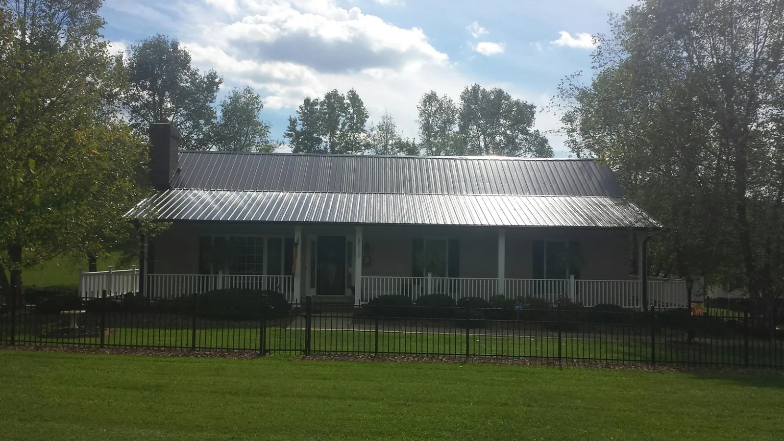 Gray metal roof on a brick ranch with a full width front porch — Gutter Guard Installation work by our crew in Pingree