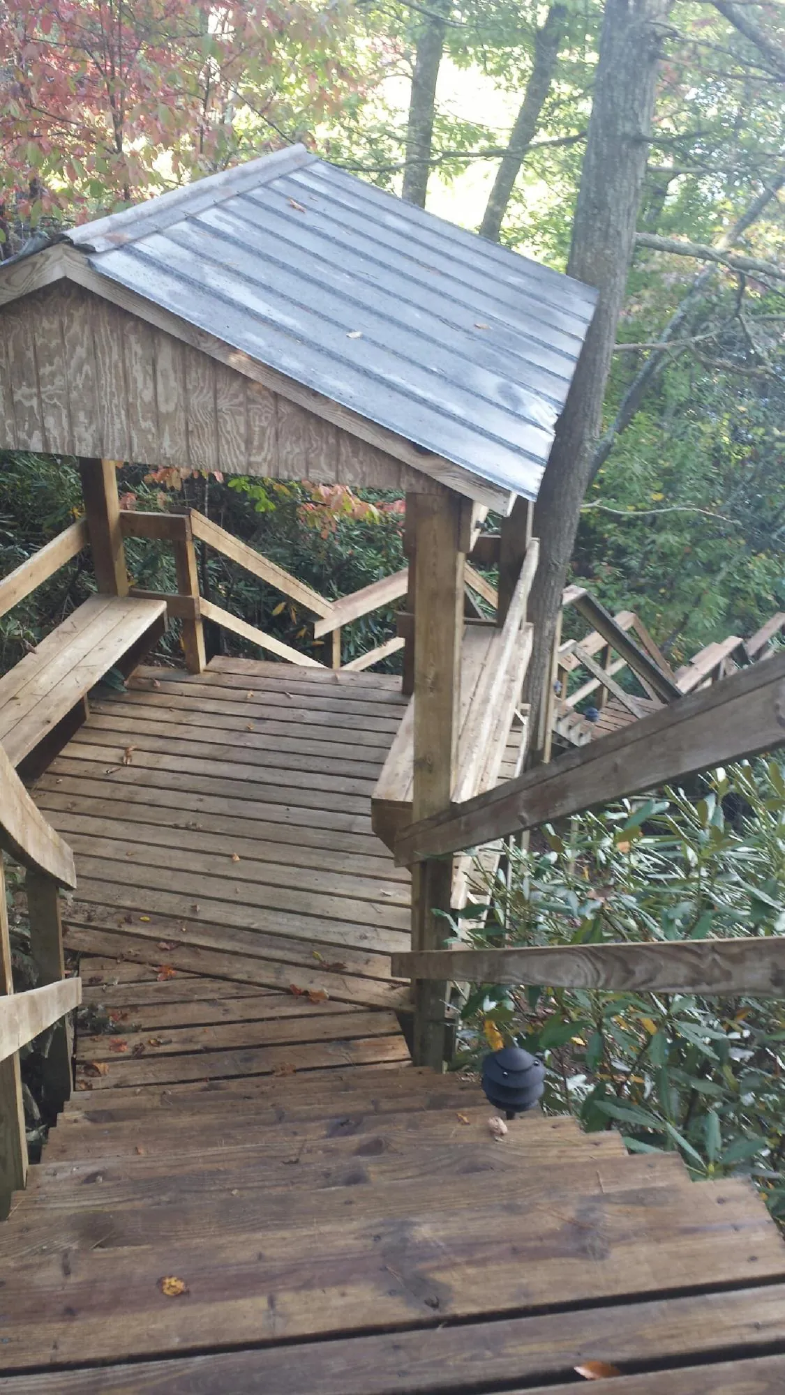Metal roofed shelter over wooden steps on a wooded walkway — Skylight Repair & Installation work by our crew in Pingree