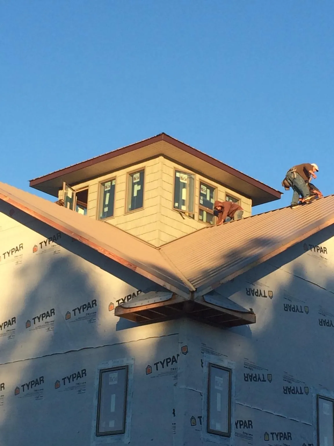 Roofers working around a rooftop cupola on a new metal roof at sunset — Roof Waterproofing in Pingree by Roofing Brothers